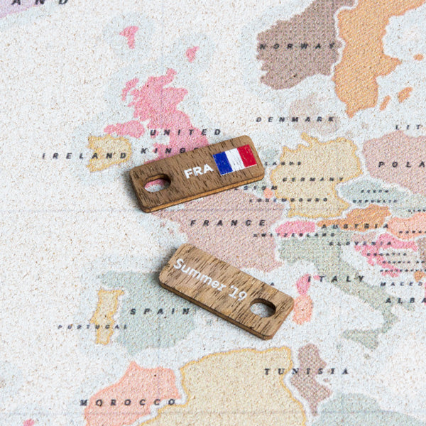 Tag de Francia mostrando su reverso también personalizable, encima de un mapa watercolor